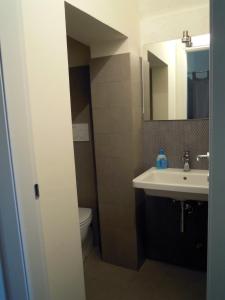 bagno con lavandino, servizi igienici e specchio di B&b Il Cortile a Matera