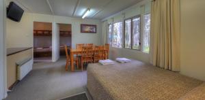 Schlafzimmer mit einem Bett, einem Tisch und Stühlen in der Unterkunft Kosciusko Tourist Park in Jindabyne