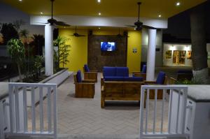 a lobby with blue chairs and a tv on a wall at Eco Bay Hotel in Bahía Kino