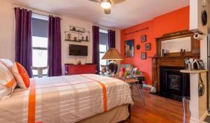 um quarto com paredes cor de laranja, uma cama e uma lareira em Fabulous Fully Furnished Studio Minutes From Times Square! em Nova Iorque