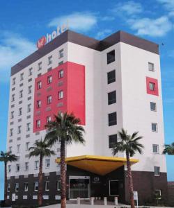 un bâtiment d'hôtel avec des palmiers devant lui dans l'établissement Hotel Hi ! Torreon Aeropuerto-Galerías, à Torreón