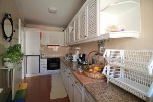 a kitchen with white cabinets and a counter with fruit in baskets at Cabedelo Spot - Beachside Vacations in Viana do Castelo +27 photos