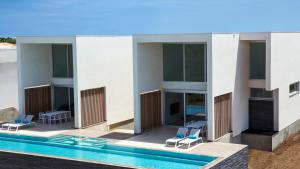 a building with a swimming pool and two blue chairs at CARAIBAS Bonaire modern air-conditioned vacation home for architectural design lovers in Belnem
