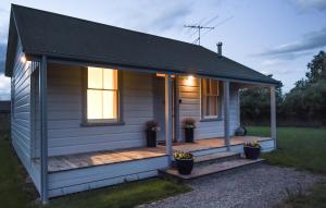 Cette petite maison blanche dispose d'une terrasse couverte. dans l'établissement The Vicarage Martinborough, à Martinborough