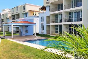 an apartment building with a swimming pool in front of it at Sunset Paradise - Ocean View Penthouse Apartment in Cabo Rojo