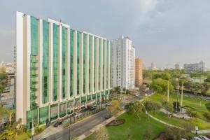 a large white building in a city with a park at Delfines Hotel & Convention Center in Lima