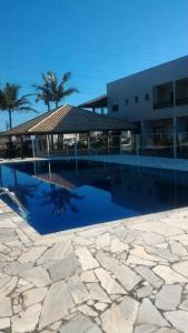 a large swimming pool next to a building with palm trees at Murakami Pousada in Itanhaém