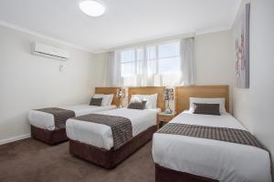 a bedroom with two beds and a window at Mid City Motel Warrnambool in Warrnambool