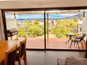d'un salon avec une grande porte en verre s'ouvrant sur une terrasse. dans l'établissement Omaroo House - panoramic water views, à Hobart