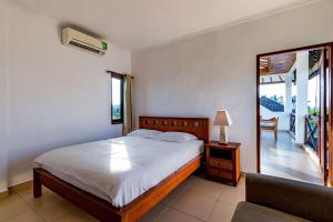 a bedroom with a bed and a chair and a mirror at Medewi Surf Villa in Pulukan