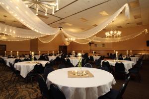 un salón de banquetes con mesas y sillas blancas y lámparas de araña en Barkers Island Inn Resort & Conference Center, en Superior