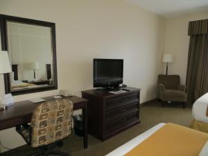 een hotelkamer met een bureau, een televisie en een spiegel bij Holiday Inn Express & Suites Whitecourt, an IHG Hotel in Whitecourt