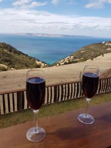 two glasses of wine sitting on a table overlooking the ocean at Trading Places Kangaroo Island in Penneshaw