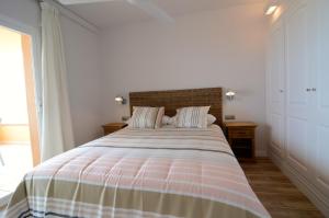 a bedroom with a large bed with a striped blanket at Golf Mar II G 1-2 in Pals +28 photos