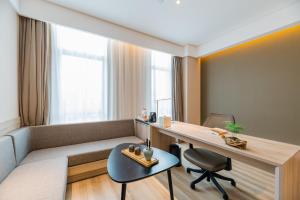 a room with a couch and a desk and a chair at Atour Hotel (Nanjing Xingang Development Area) in Nanjing