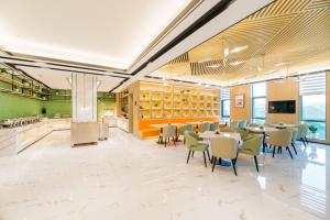 a dining room with tables and chairs and a kitchen at Atour Hotel (Nanjing Xingang Development Area) in Nanjing