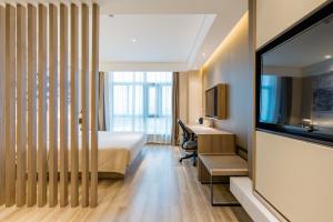 a hotel room with a bed and a desk and a television at Atour Hotel (Nanjing Xingang Development Area) in Nanjing