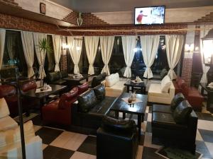 a restaurant with couches and tables and a tv at Tiara Hotel in Dobrich