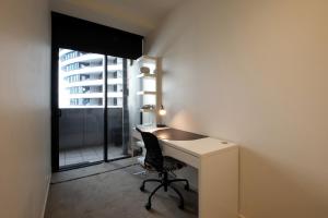a desk with a chair in a room with a window at ACD Apartments in Melbourne
