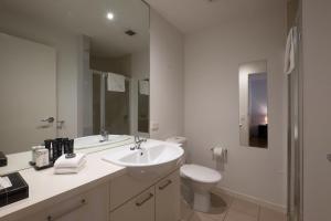 a white bathroom with a sink and a toilet at ACD Apartments in Melbourne