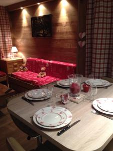 une table avec des assiettes, des verres et un canapé rouge dans l'établissement Prariond 5, à Tignes
