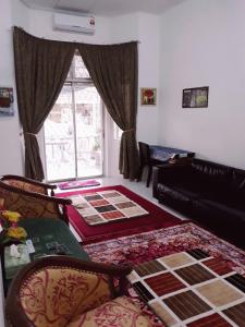 TSA Jitra Homestay في Kampong Pantai Halban: غرفة معيشة مع أريكة ونافذة