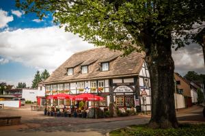 un gran edificio con sombrillas rojas delante en Hotel Hellers Krug, en Holzminden