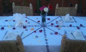 a white table with a vase and flowers on it at Dar Dikrayat in Marrakesh