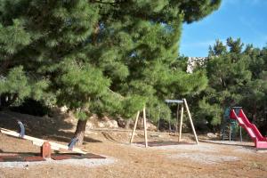 a playground with play equipment in a park with trees at Miraluna Aparthotel in Lefkos Karpathou