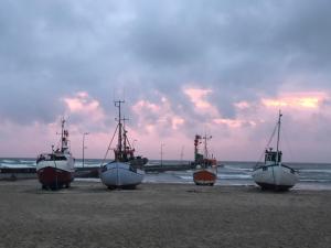 três barcos sentados numa praia perto do oceano em Luksus i Løkken em Lokken