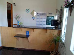 a cashier counter in a waiting room with a plant at Economy Inn Morgan Hill in Morgan Hill