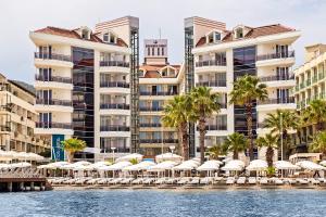 een uitzicht op het resort vanaf het water met stoelen en parasols bij Poseidon Hotel - Adult Only in Marmaris