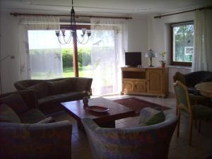 ein Wohnzimmer mit Sofas, einem Tisch und einem TV in der Unterkunft Haus Halligblick - Ferienwohnungen am Meer in Dagebüll