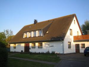 ein weißes Haus mit braunem Dach in der Unterkunft Haus Halligblick - Ferienwohnungen am Meer in Dagebüll