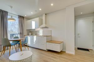 una cucina con armadi bianchi, tavolo e sedie di Center Apartment 10A a Vilnius