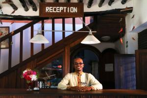 a man sitting at a bar in a restaurant at Blue Oyster Hotel in Jambiani