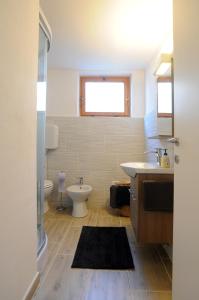 uma casa de banho com um lavatório, um WC e uma janela. em Casa Polsa "1964" em Brentonico