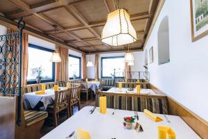 ein Restaurant mit Tischen, Stühlen und einem Kronleuchter in der Unterkunft Hotel Schönwies in Truden