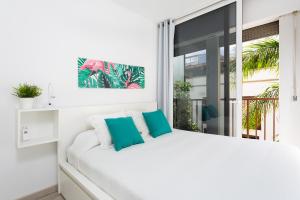 a white bedroom with a white bed and a window at Monkey house in Santa Cruz de Tenerife