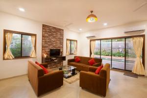a living room with two couches and a tv at SaffronStays Dhyana, Vikramgad in Pālghar