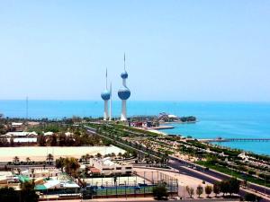 Blick auf eine Stadt mit zwei Türmen und das Meer in der Unterkunft Bravo Royal Hotel Suites in Kuwait