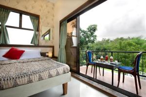a bedroom with a bed and a balcony with a table and chairs at SaffronStays Nithyam, Vikramgad in Pālghar