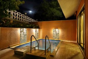 a swimming pool at night with lights on the wall at SaffronStays Nithyam, Vikramgad in Pālghar