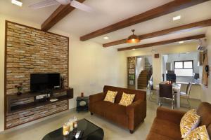 a living room with a couch and a brick wall at SaffronStays Nithyam, Vikramgad in Pālghar