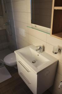 a bathroom with a white sink and a toilet at Petite Apartment in Maribor +10 photos