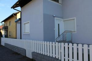 a white picket fence next to a white house at Petite Apartment in Maribor