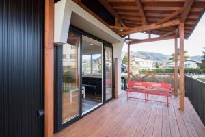 a porch with a red bench on a wooden deck at Hakuba Downtown Apartments in Hakuba