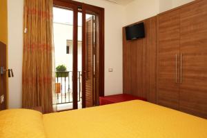 ein Schlafzimmer mit einem gelben Bett und einer Glasschiebetür in der Unterkunft Coralia Bed & Breakfast in San Vito lo Capo