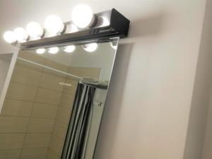 a bathroom with a mirror with lights above a shower at Dimora Apartments with free parking in Ljubljana +37 photos
