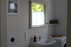 a white bathroom with a sink and a window at rosmarin-am-sund in Altefähr +15 photos